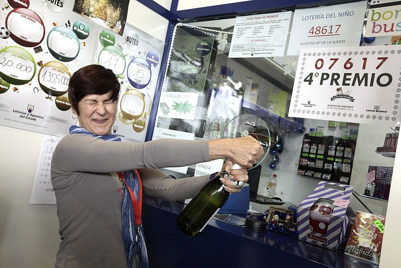 La empleada de una gasolinera de La Laguna (Tenerife), abre una botella para celebrar que ha vendido por terminal el número 07.617, premiado con un cuarto premio.