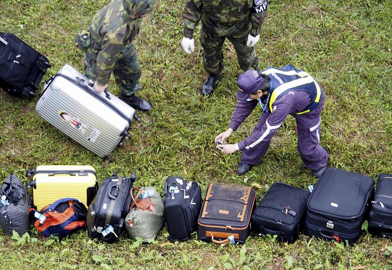 Un policía toma fotografías de las maletas de los pasajeros del avión siniestrado