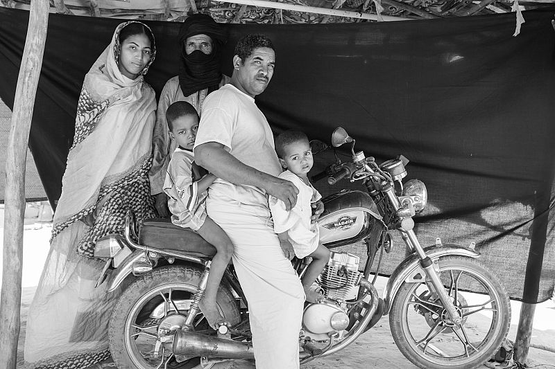 Abdou Ag Moussa, de 34 años, sentado junto a su familia sobre la moto que les salvó la vida.