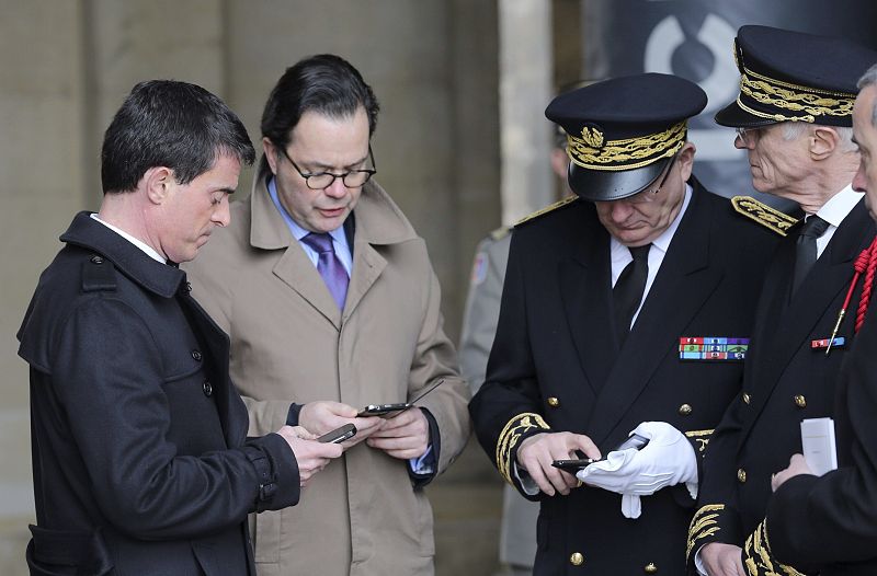 El primer ministro francés, Manuel Valls (i), consulta en su móvil la noticia del accidente poco antes de recibir a los reyes españoles.