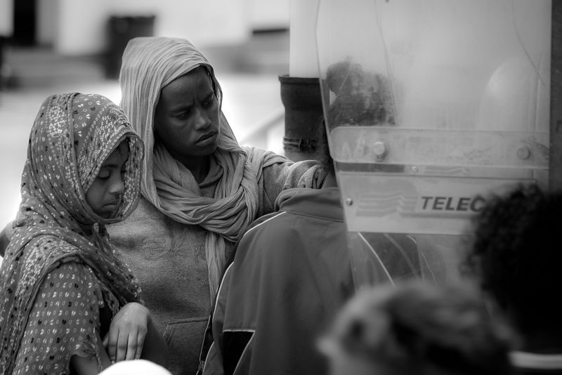 Recién llegados a Lampedusa, hacen cola en la cabina telefónica para contactar con su familia.