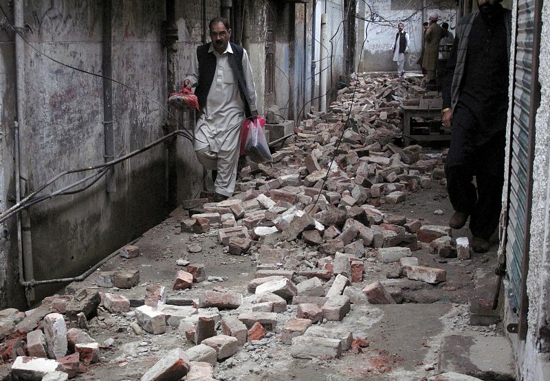 Un viandante intenta esquivar los cascotes caídos a causa del terremoto en la ciudad de Mingora, en Pakistán