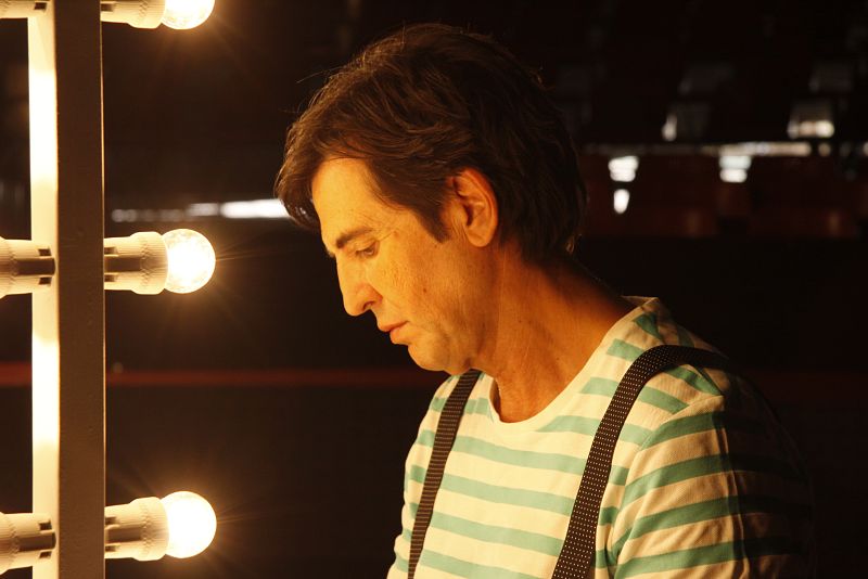 Frente al espejo de maquillaje, entre las bambalinas del escenario, Manolo Tena se prepara para el concierto