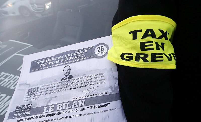 Una octavilla sobre la huelga convocada por los taxistas franceses sobre el parabrisas de uno de los vehículos que ha bloqueado el acceso al aeropuerto de Roissy