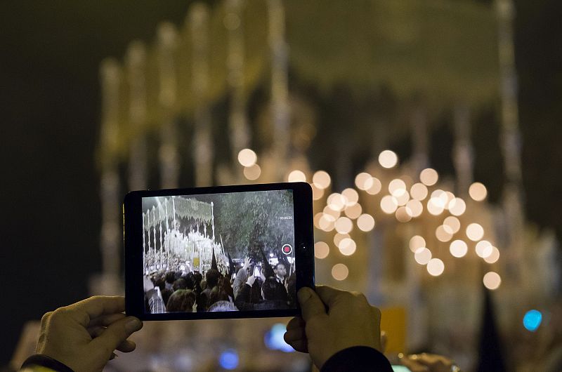 Una persona graba con su tableta el paso de palio de la Esperanza en Sevilla
