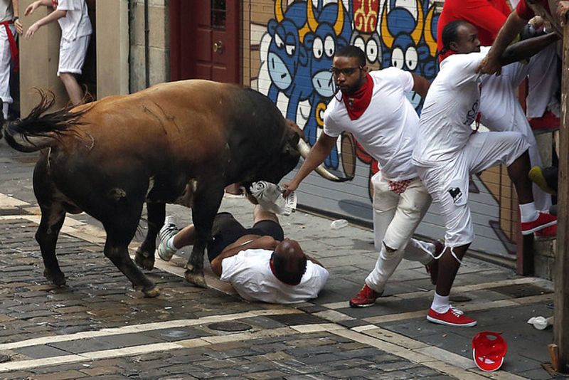 Un toro de la ganadería de Cebada Gago embiste a un mozo a su paso por la curva de Mercaderes. Finalmente, seis corredores han sido trasladados con cornadas al Complejo Hospitalario de Pamplona.