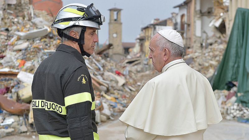 El papa Francsico habla con un bombero durante su visita a Amatrice, Italia, el 4 de octubre de 2016. Amatrice fue el pueblo más golpeado por el terremoto del 24 de agosto que mató a 300 personas. AFP PHOTO / OSSERVATORE ROMANO