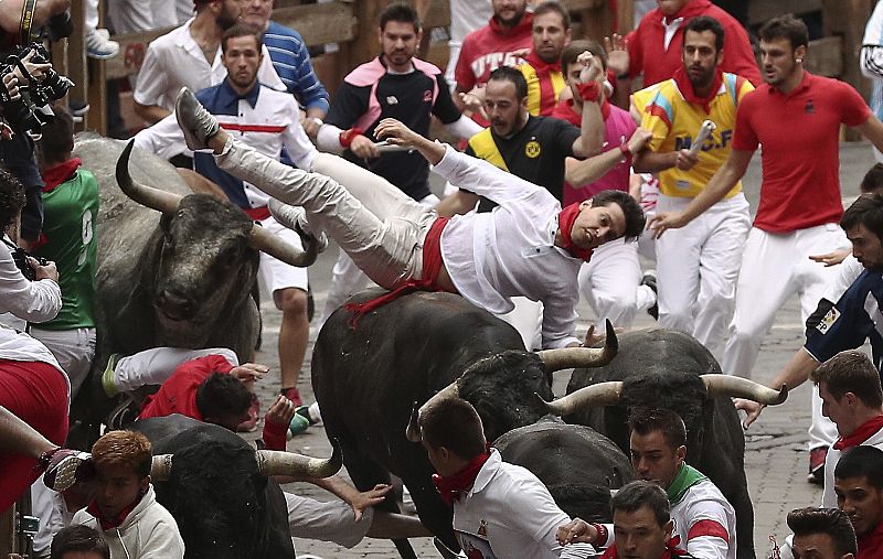 Los toros arrollan a un grupo de corredores en el tramo de Telefónica Los astados de Miura voltean a un mozo en el tramo final que precede al callejón de entrada a la Plaza de Toros durante el octavo y último encierro