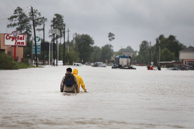 Dos residentes caminan por una avenida completamente anegada de Houston