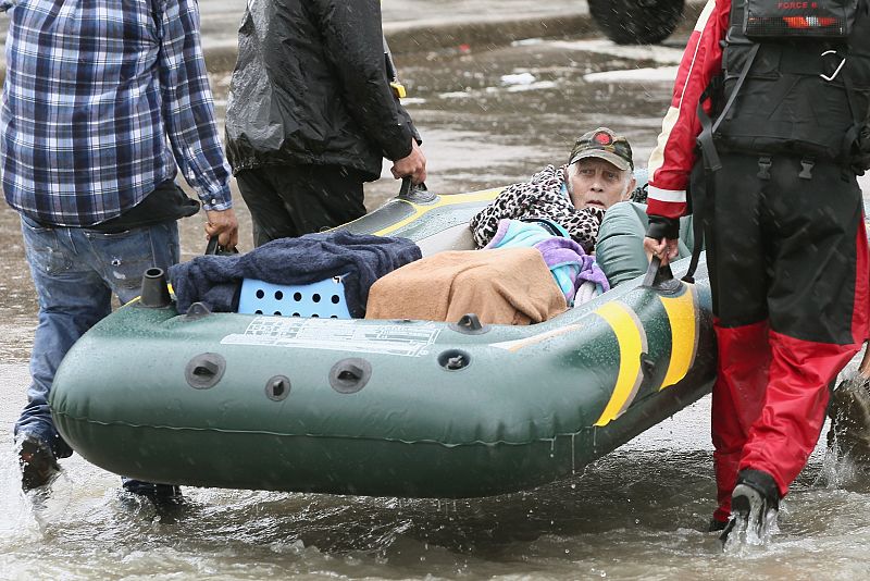 Varios agentes de los servicios de rescate y voluntarios trasladan a un anciano rescatado en un barrio de Houston