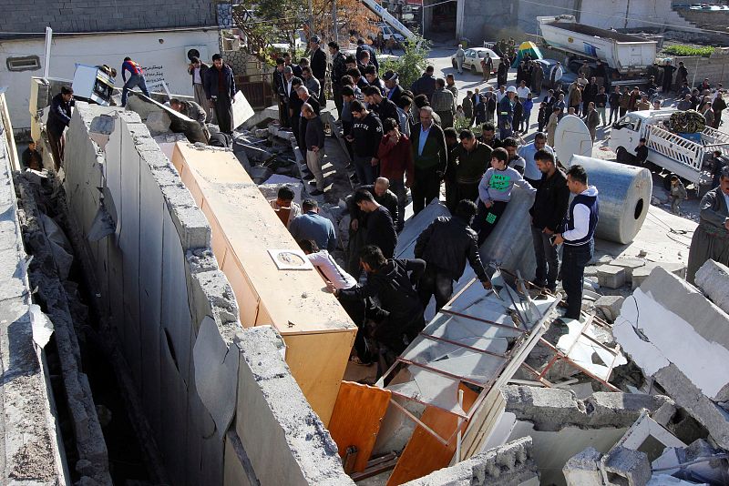 Gente trata de recuperar enseres de uno de los edificios que se han derrumbado en Darbandikhan, Irak