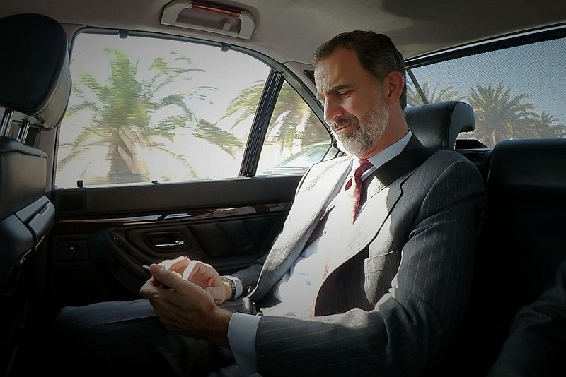 El rey sonríe al consultar su móvil a su llegada al V Foro Internacional de Turismo Maspalomas Costa Canaria