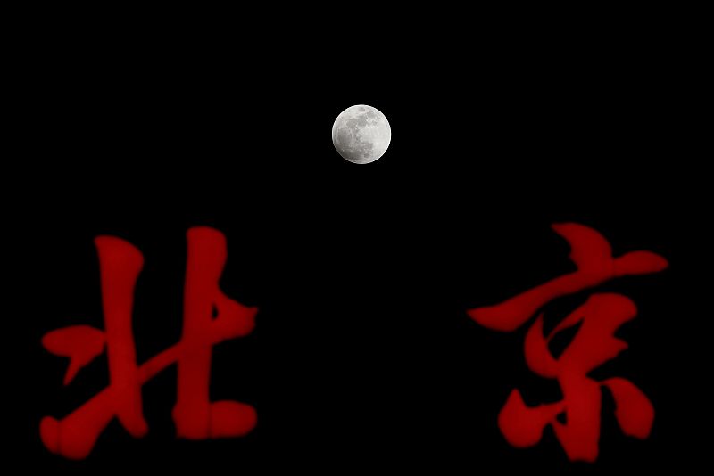 La superluna azul sobresale de las letras de un cartel, en un edificio de la ciudad china de Pekín.