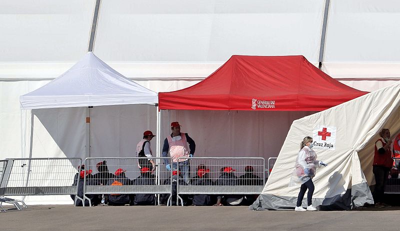 Varias personas permanecen a la espera del procedimiento tras desembarcar del barco italiano Dattilo