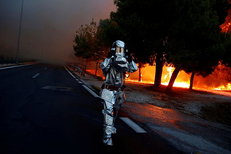 Un bombero con un traje de aproximación al fuego en el incendio de Rafina.