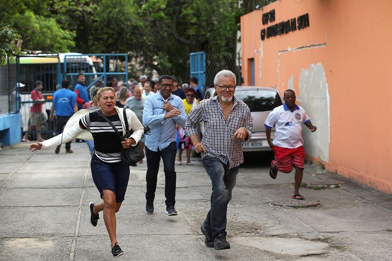 Votantes entran corriendo en el colegio electoral en la Favela de Rocinha, en Río de Janeiro