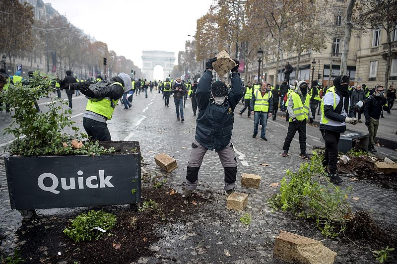 Un manifestante sostiene un adoquín sobre los Campos Elíseos