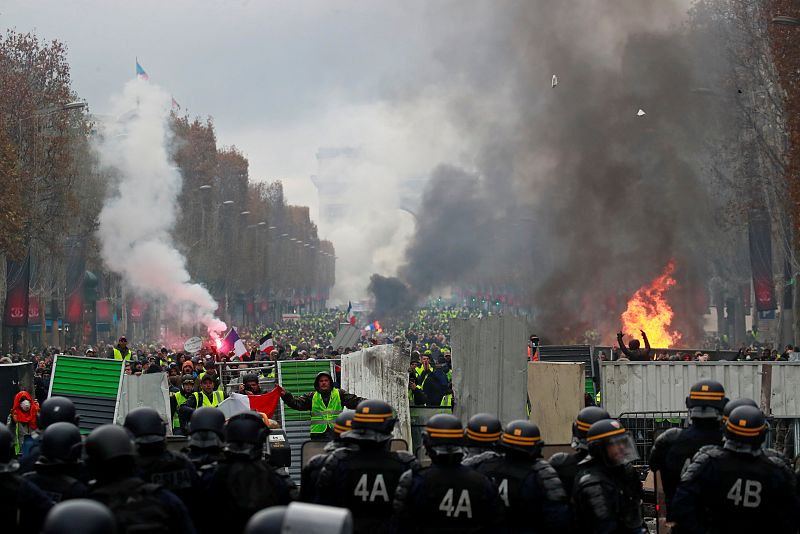 Los manifestantes se parapetan tras una barricada en los Campos Elíseos