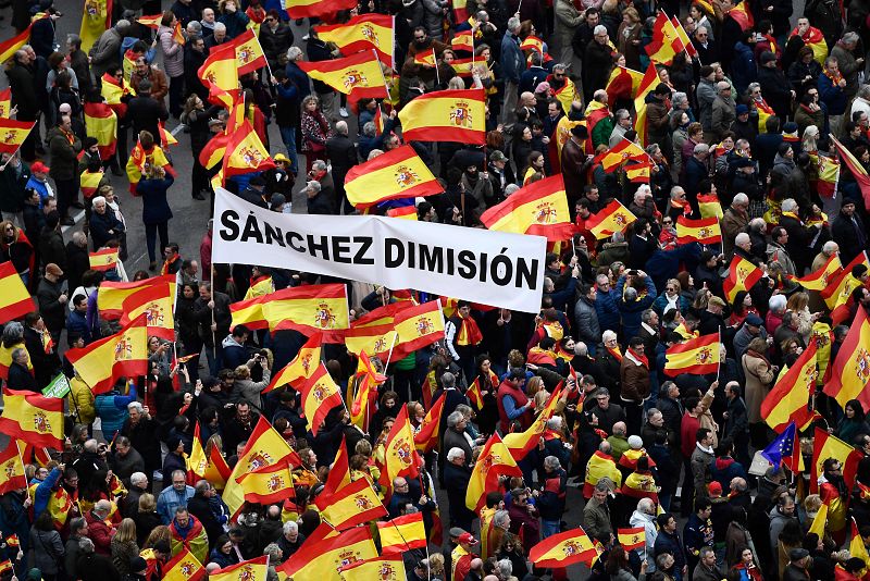 Un grupo de asistentes a la concentración en la plaza de Colón porta una pancarta que reza "Sánchez dimisión"