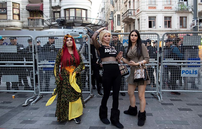 Tres mujeres tránsgenero intentan cruzar a la calle adyacente mientras la policía turca impide el paso para evitar la marcha con motivo del Día Internacional de la Mujer, este viernes en Estambul (Turquía).