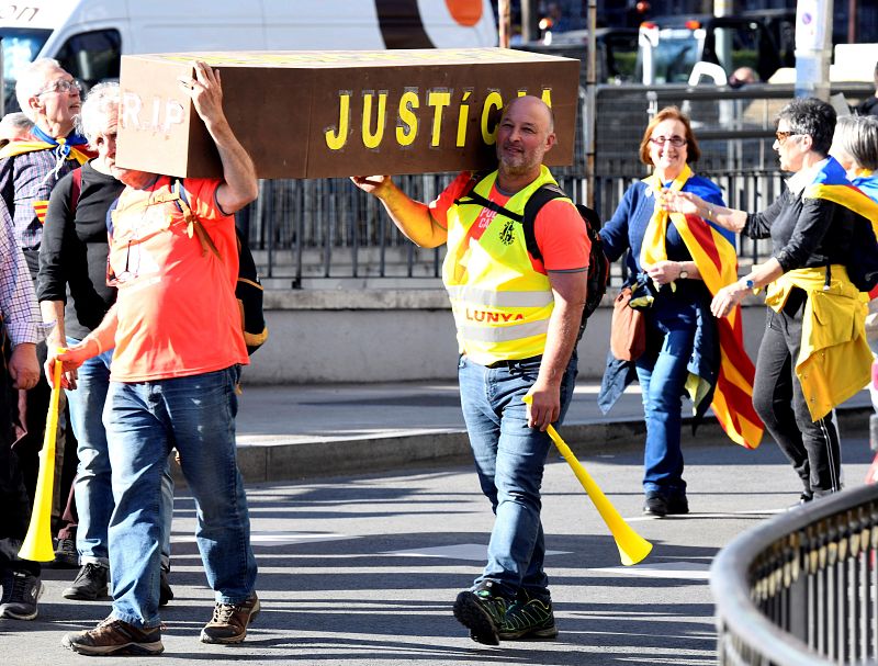 Dos personas portan un ataúd en el que se puede leer la palabra Justicia