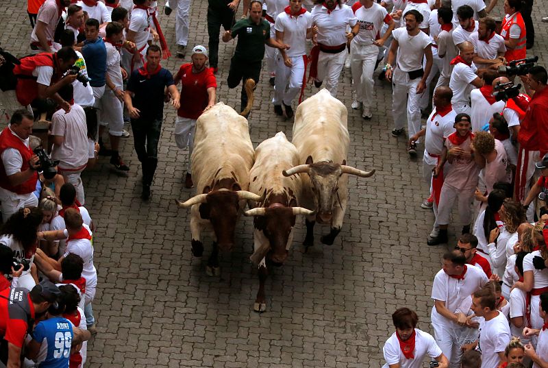 Los participantes corriendo delante de los toros de la ganadería del Puerto de San Lorenzo en el primer encierro de los Sanfermines 2019. 