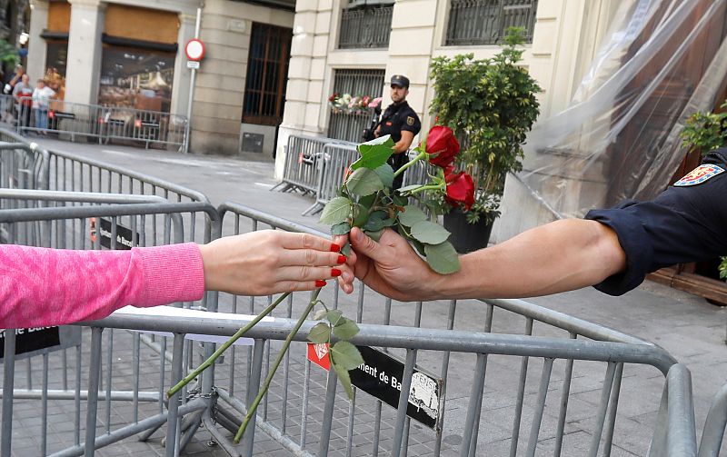 Una mujer entrega flores a un agente a las puertas de la Jefatura de Policía en Barcelona.