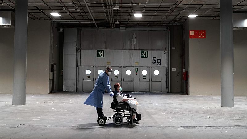 Un sanitario traslada a una paciente con coronavirus en el hospital de campaña instalado en el recinto ferial de Madrid.