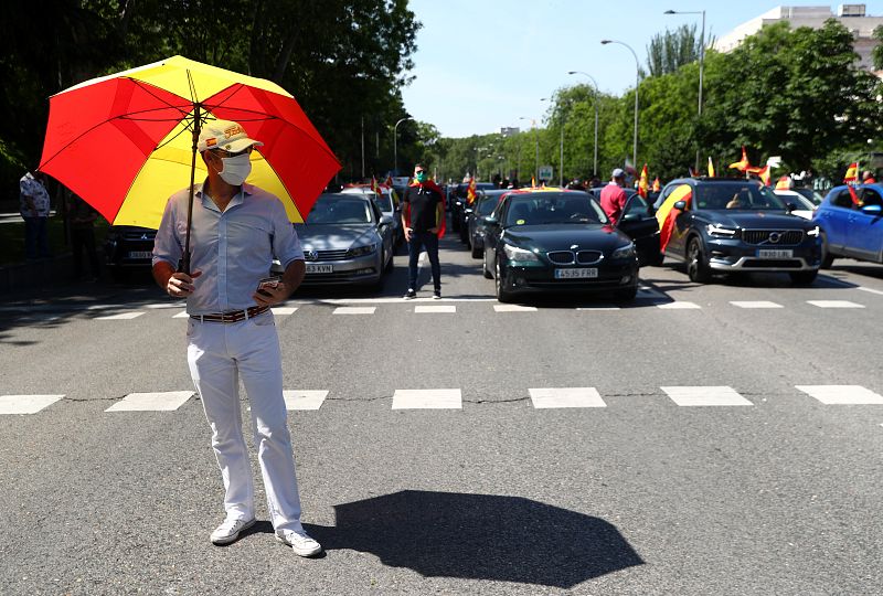 Un manifestante con mascarilla y paraguas con la bandera española protesta este sábado en Madrid.