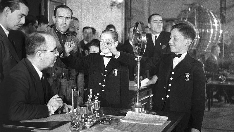 Madrid, 22-12-1939.- Los niños del colegio de San Ildefonso, que cantaron el "Gordo", muestran las bolas agraciadas para su comprobación, durante el sorteo extraordinario de la Lotería de Navidad.