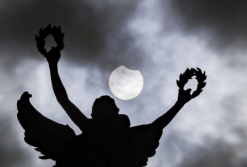El fenómeno astronómico, visto detrás de una estatua en el parque Jubilee de Bruselas.