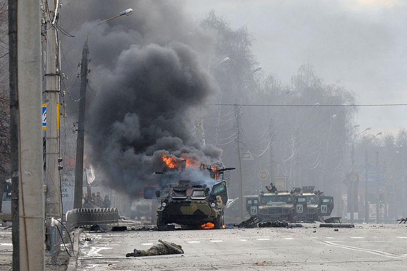 Un vehículo blindado de transporte de personal ruso (APC) ardiendo junto al cuerpo de un soldado no identificado durante la lucha con las fuerzas armadas ucranianas en Kharkiv.
