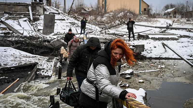 Civiles cruzan un río por un puente volado en el norte de Kiev.