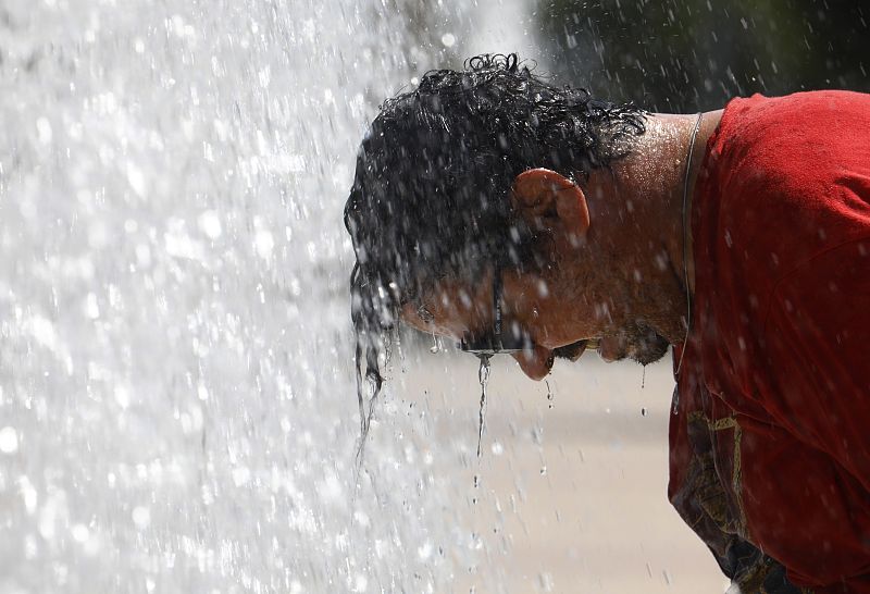 Un hombre se refresca en una fuente pública del centro de Córdoba.