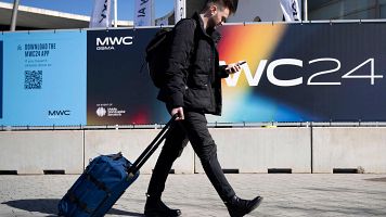 Un congresista mirando el m�vil mientras pasa por delante de Fira Barcelona, sede del Mobile World Congress