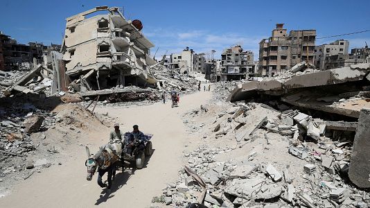 Palestinos conducen un carro entre los escombros de las casas, en la ciudad de Gaza, el 20 de mayo de 2025
