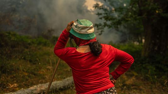 Una vecina de la aldea de Pareiss lucha contra en fuego en el incendio forestal que permanece activo en A Pobra de Trives