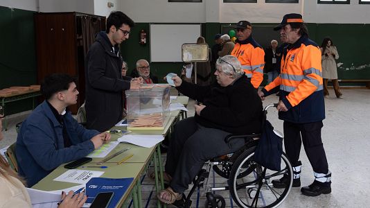 Un hombre en silla de ruedas recibe ayuda para acudir a votar a uno de los colegios de M�rida