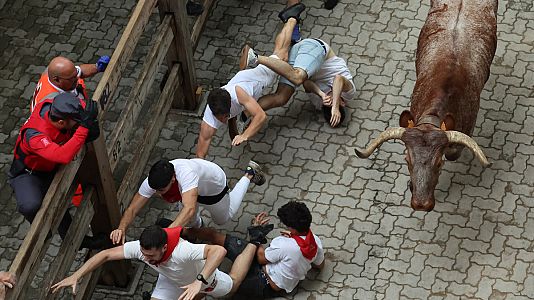 Varios mozos se tropiezan al paso de uno de los toros de la ganadera de Nez del Cuvillo durante el quinto encierro de los sanfermines 2023