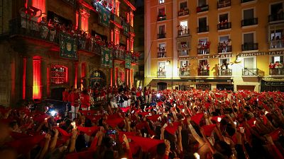 Los asistentes sostienen pauelos rojos y velas, mientras cantan la tradicional cancin de despedida "Pobre de mi"