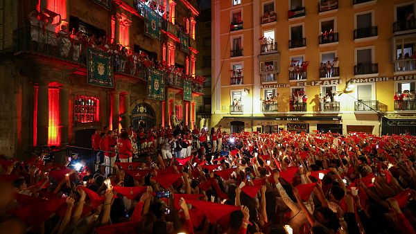 Los asistentes sostienen pauelos rojos y velas, mientras cantan la tradicional cancin de despedida "Pobre de mi"