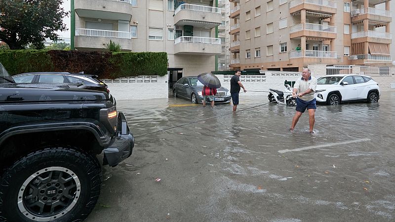 Residentes de Gand�a ayudan a un vecino a sacar su veh�culo de un garaje inundado este lunes.