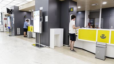 Un joven es atendido en una oficina de Correos en Madrid