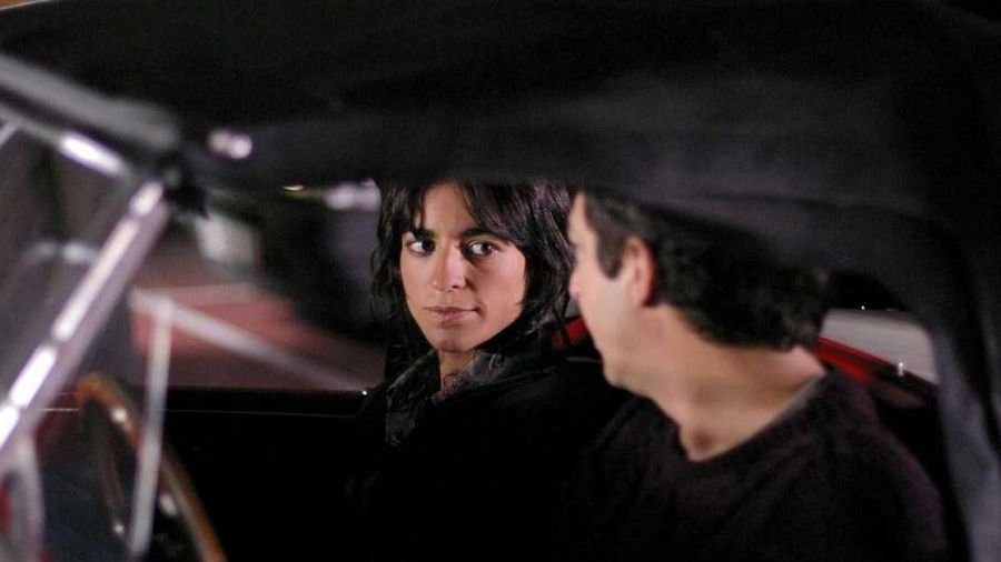 Dos personas conversan dentro de un coche descapotable en una escena de 'La educación de las hadas'.
