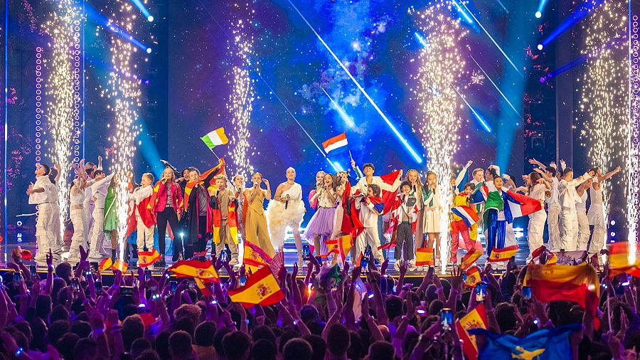 Inauguración de Eurovisión Junior 2024 con los participantes y sus banderas en un escenario lleno de luces y fuegos artificiales.
