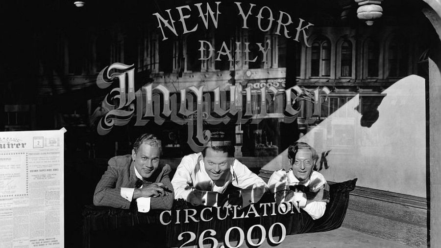 Fotografía promocional de "Ciudadano Kane" con tres hombres en la ventana de la redacción del New York Daily Inquirer.