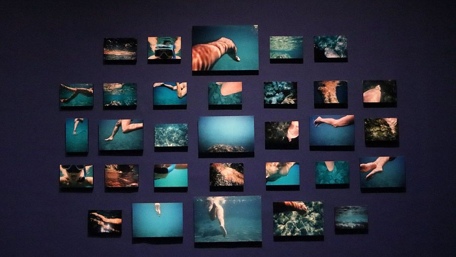 Fotografías de Mari Chordà (2011) mostrando partes del cuerpo sumergidas en agua, dispuestas en cuadrícula sobre pared azul. Obra titulada "Espiroqueta".