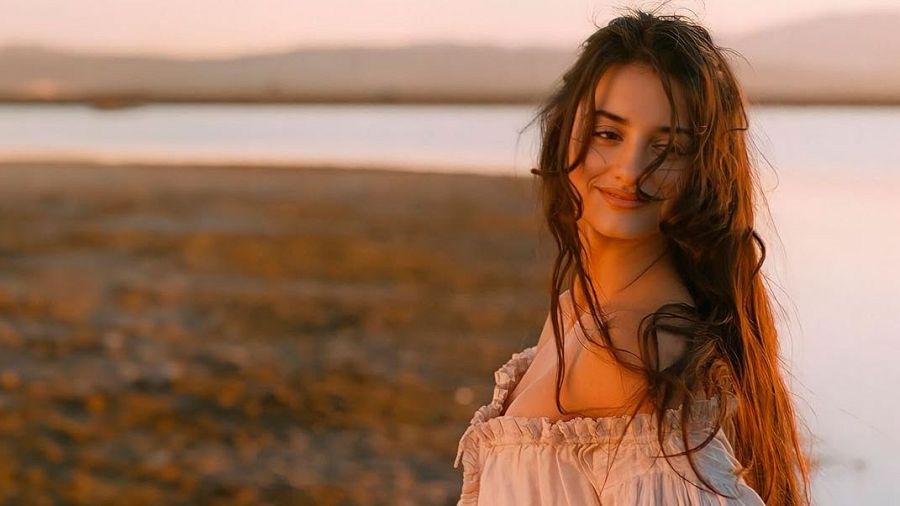 Aitana Sánchez-Gijón, actriz de "Volavérunt", con expresión serena y blusa clara, ante un paisaje al atardecer.