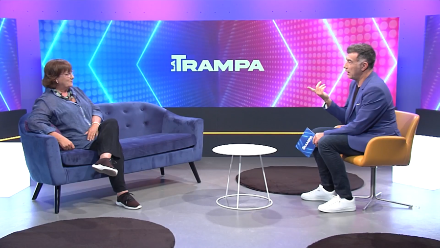 Los presentadores Olga Viza y Pep Plaza en el plató de "La Trampa".  Él gesticula mientras ella escucha; ambos en un set con sofá azul, silla mostaza y pantalla con el logo del programa.