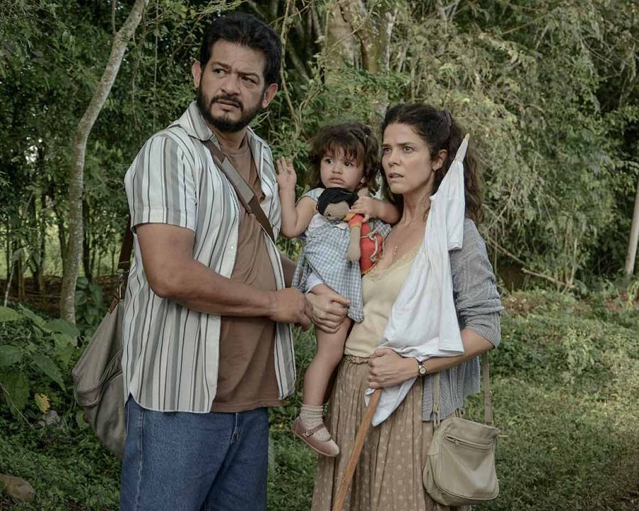 Juana Acosta y Juan Carlos Martínez en escena de "Llegaron de noche".  Ella lleva falda con lunares, él carga a una niña.  Ambiente selvático.